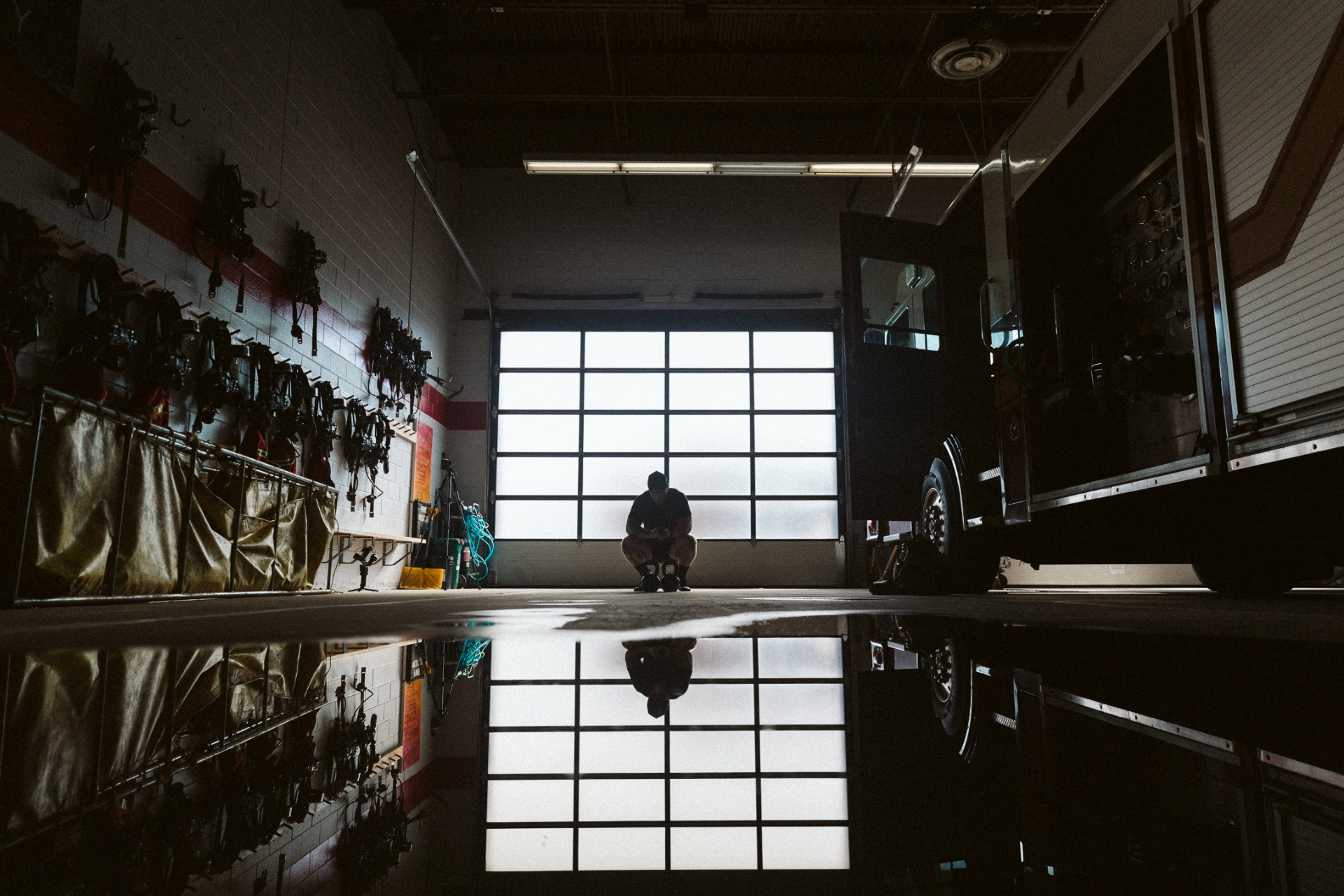 Silhouette of a firefighter working through kettlebells in the apparatus bay.